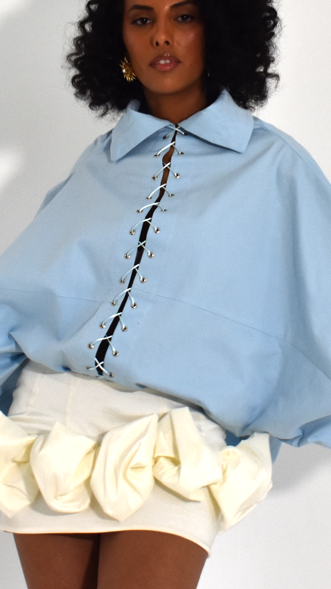 Editorial de moda Madre Atelier — detalhe de camisa azul pastel com amarração e saia esculpida
